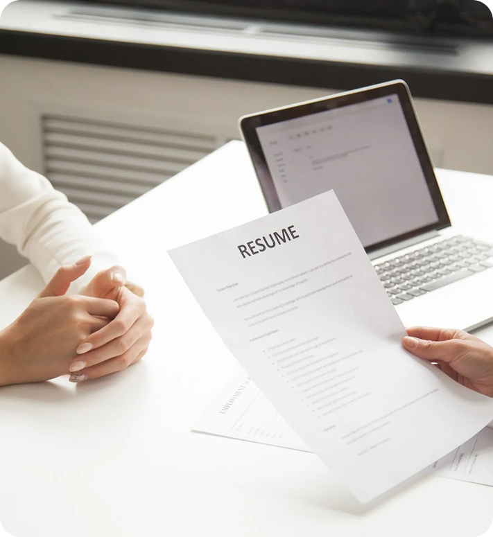 Reviewing professional resume on a desk next to a laptop